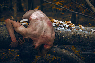 portrait d'un homme nu souffrant en forêt avec des champignons et du sang