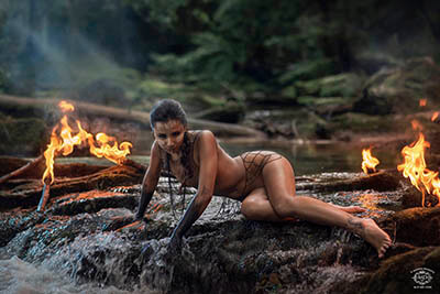 photo d'une femme dans une riviere nue dans la nature sauvage avec du feu